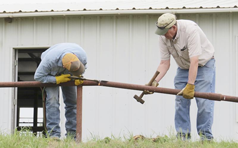 Steven James and Jim Smith remove pipe fence from around the building.  Courtesy / Star Kinder